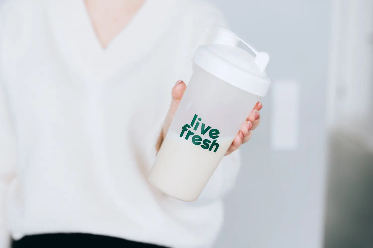 Geschlossener LiveFresh Shaker mit cremigem Slim by LiveFresh Shake in der Hand gehalten, bereit zum Mixen.